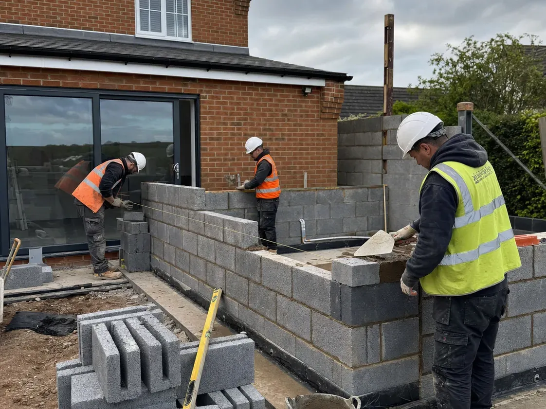 Maçons montant des murs en parpaings pour l'extension d'un pavillon