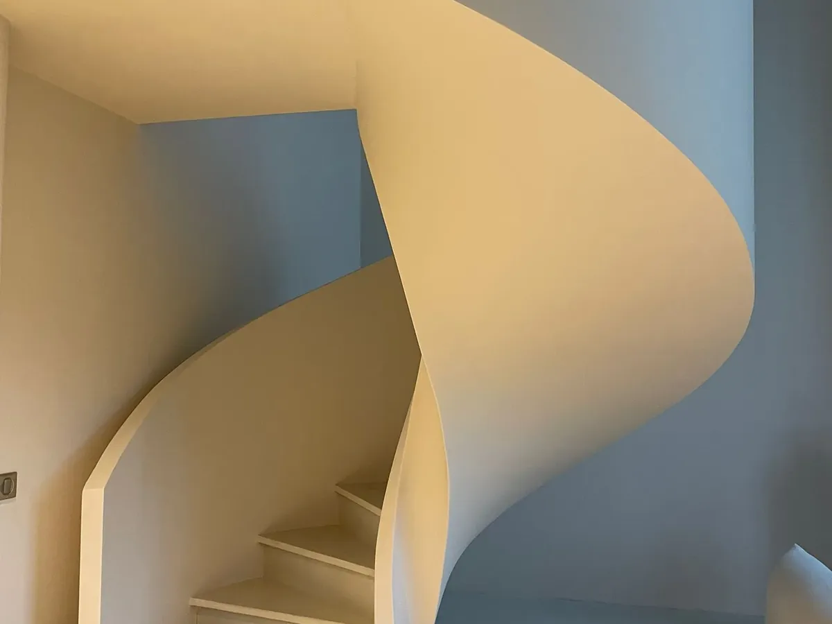 Escalier hélicoïdal blanc terminé dans une maison rénovée