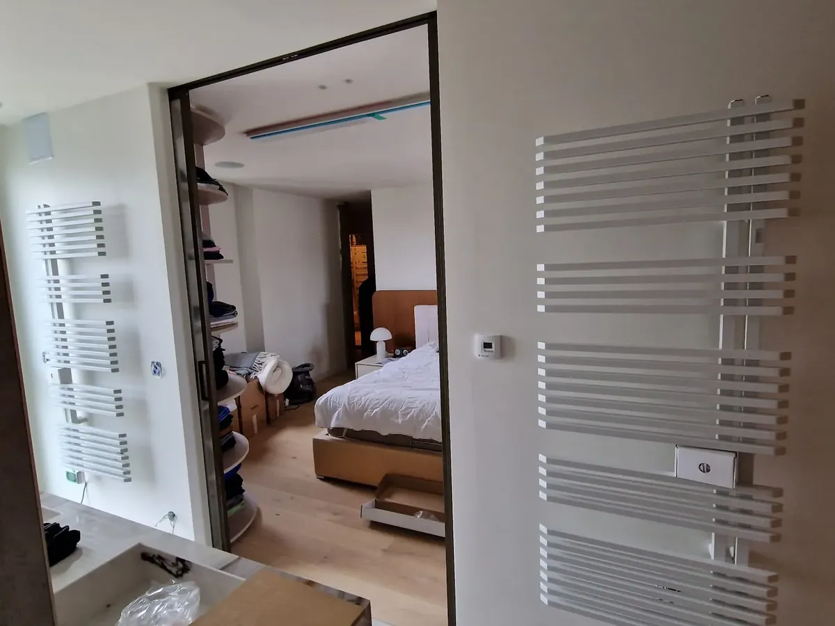 Chambre rénovée avec radiateur sèche-serviettes dans un projet de rénovation clés en main
