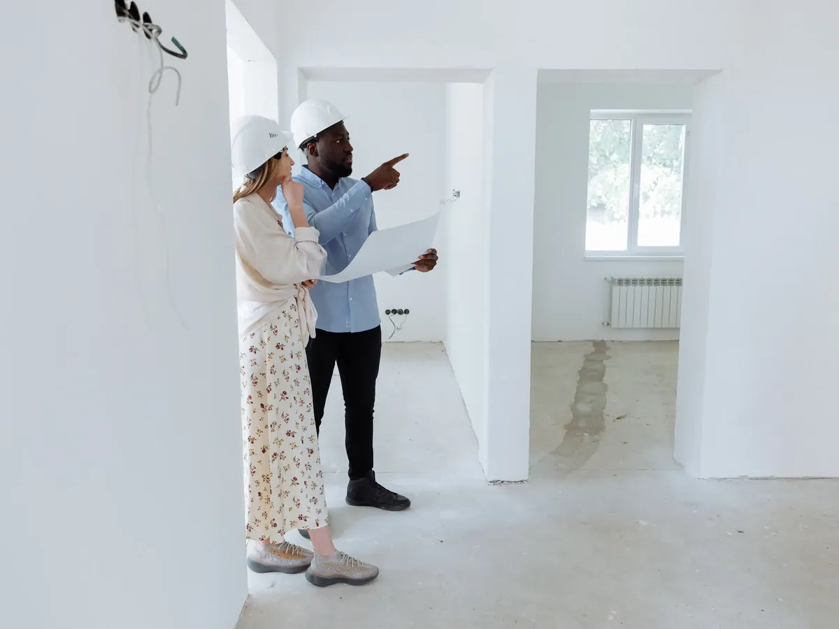 Deux professionnels examinant des plans dans un logement vide en cours de rénovation