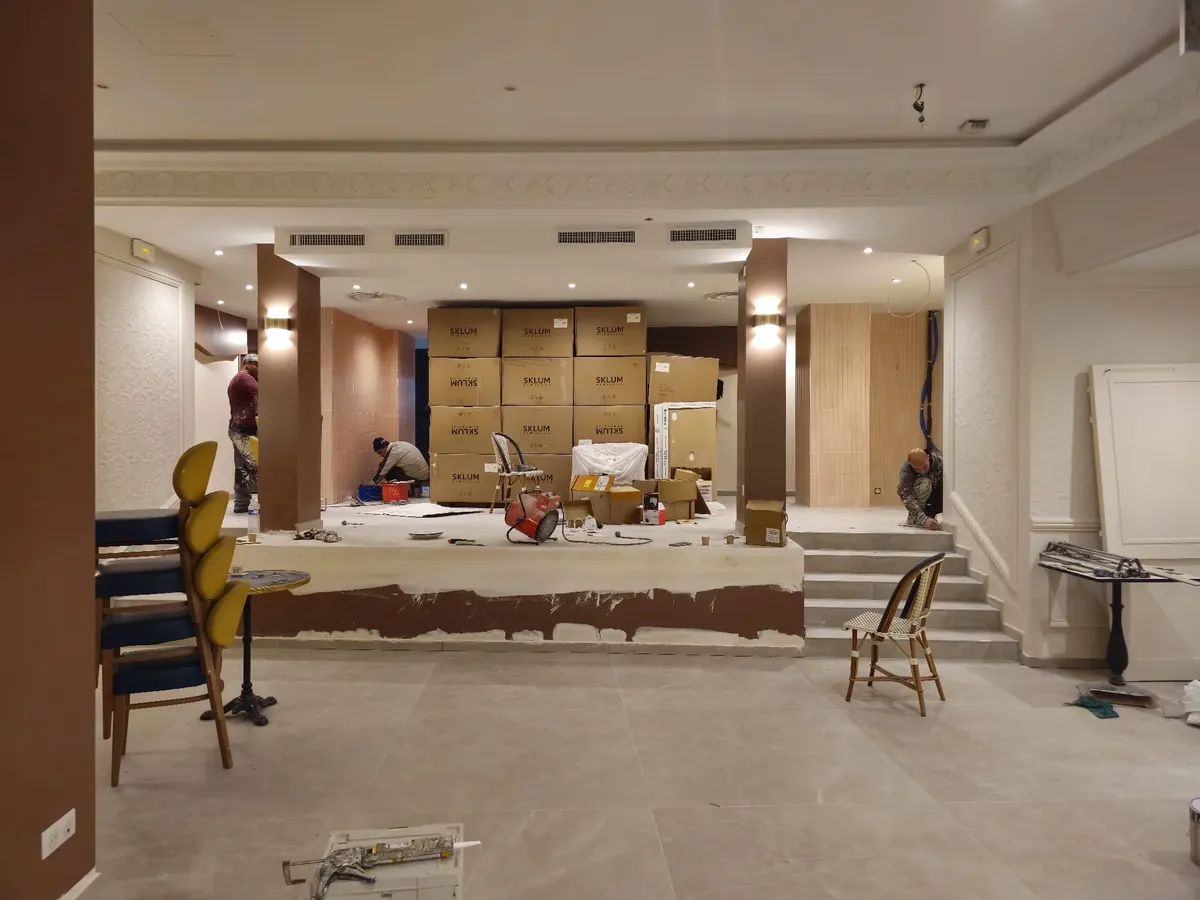 Grande salle de restaurant en travaux avant l'ouverture, colonnes et cartons de matériel